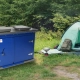 Blue TuffBoxx campground wildlife storage container installed next to tent at outdoor campsite with secure locking system