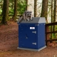 Raccoon sitting on top of a blue TuffBoxx wildlife-resistant storage container in a Canadian forest setting