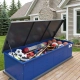 TuffBoxx blue summer storage container on residential deck holding sports equipment including basketballs, soccer balls, baseball bats and gloves demonstrating seasonal storage organization