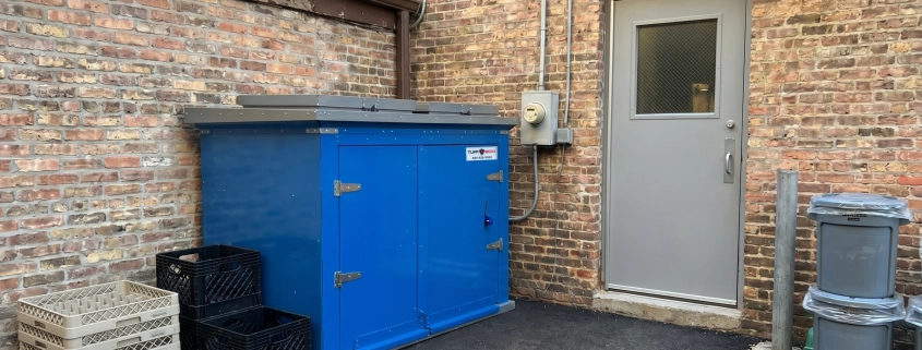 TuffBoxx commercial bins installed at restaurant loading dock showing heavy-duty blue steel construction with secure latches for wildlife-resistant waste storage